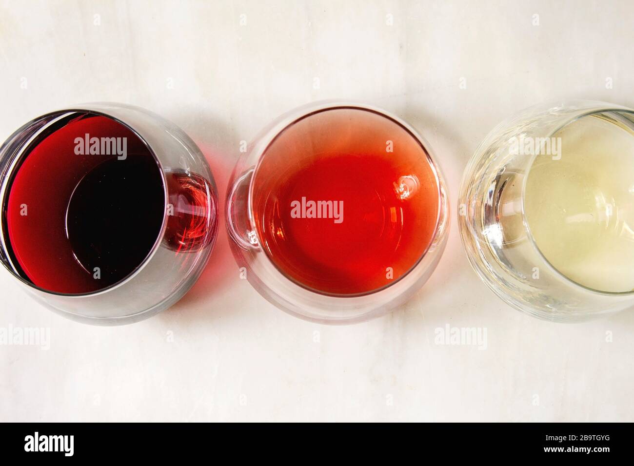 Varietà di vino. Rosso, rosa e vino bianco in Old fashion occhiali. Marmo bianco dello sfondo. Laici piana, spazio Foto Stock