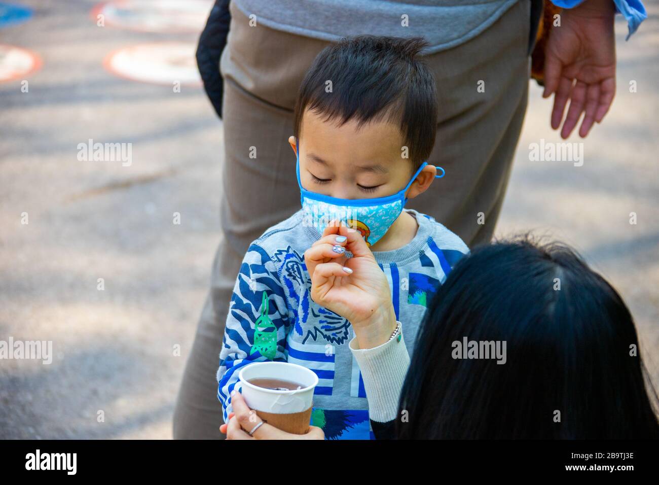 Madre che rimuove la maschera del ragazzo per bere durante la pandemia di Coronavirus, Seoul, Corea del Sud Foto Stock