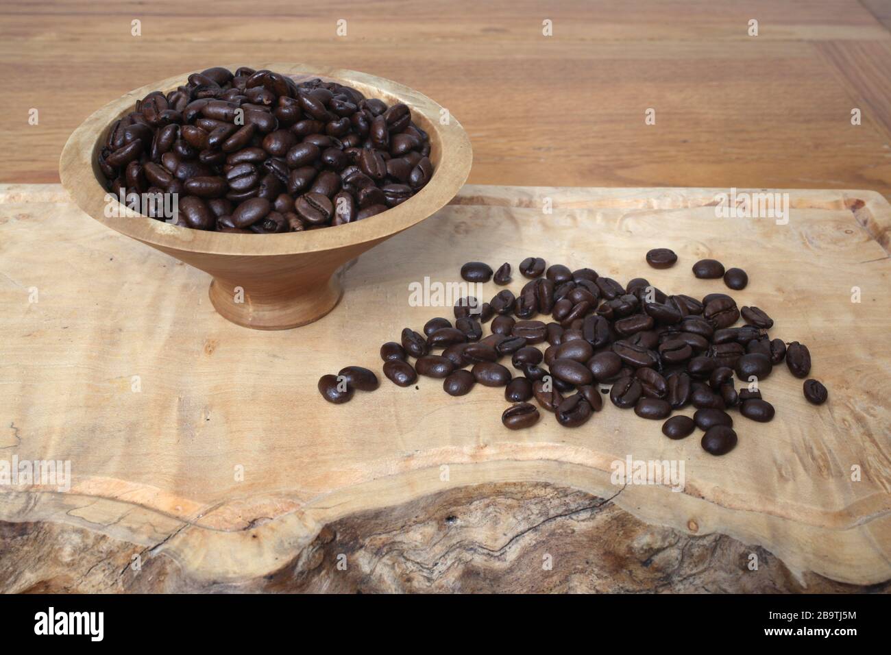 Sumatra Mandheling chicchi di caffè in una ciotola di legno e spargere fuori prima di esso. Foto Stock