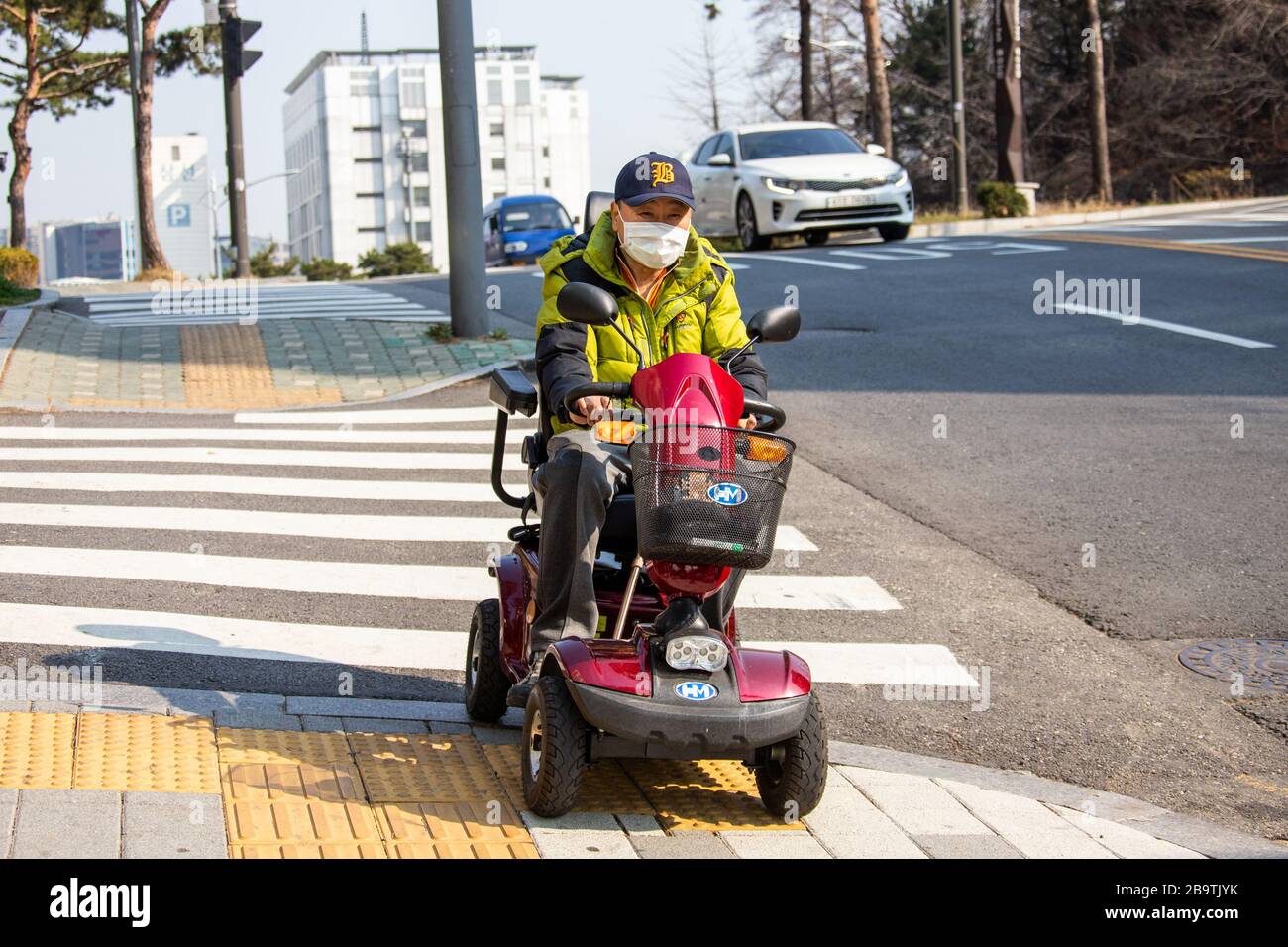 Uomo su uno scooter da mobilità senior con maschera durante la pandemia di Coronavirus, Seoul, Corea del Sud Foto Stock