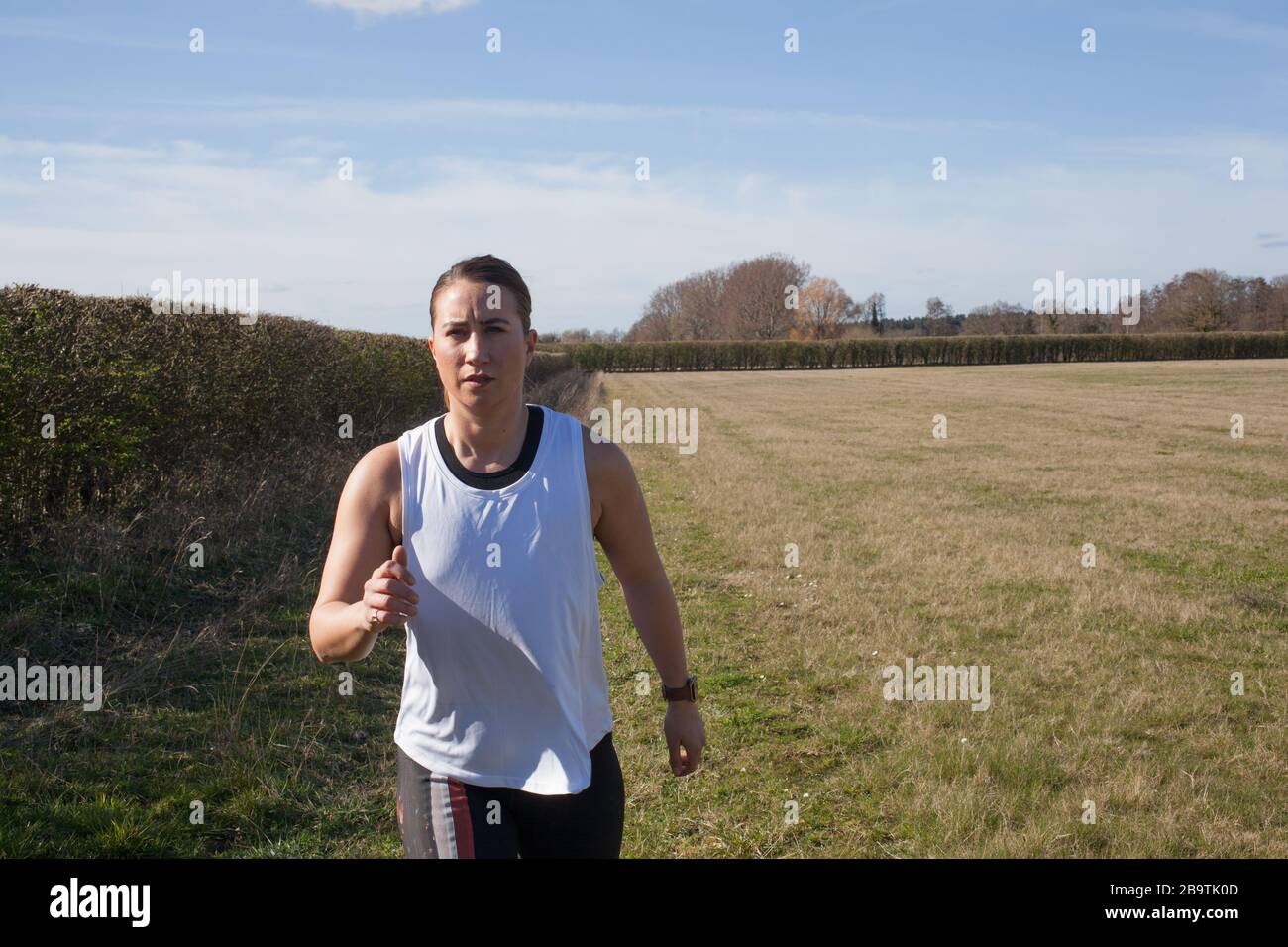 Una donna che fa jogging fuori in una fattoria Foto Stock