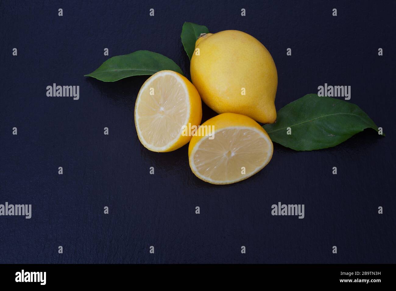 Due limoni su uno sfondo di ardesia nera Foto Stock