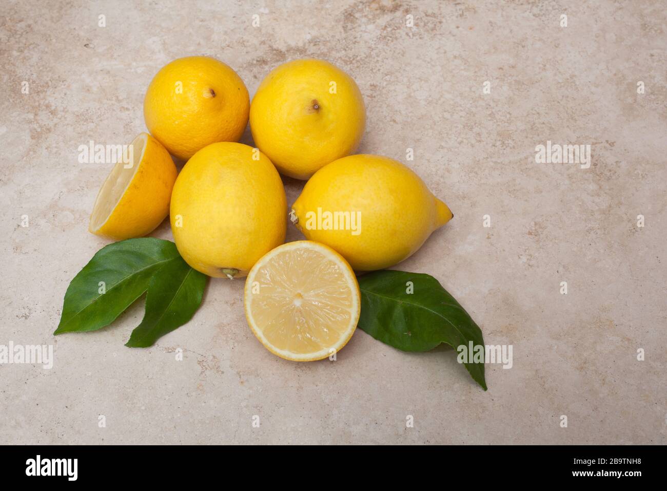 Limoni su uno sfondo chiaro con foglie Foto Stock