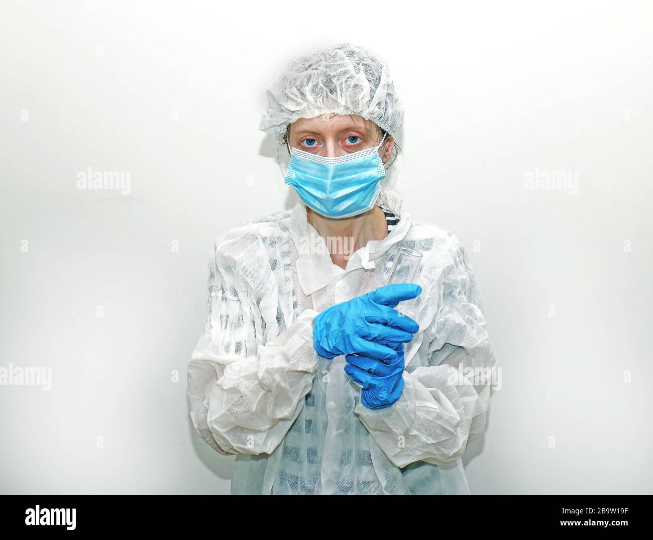Donna che indossa una maschera protettiva per il viso, un copritesta e un abito all'interno del reparto ospedaliero Foto Stock