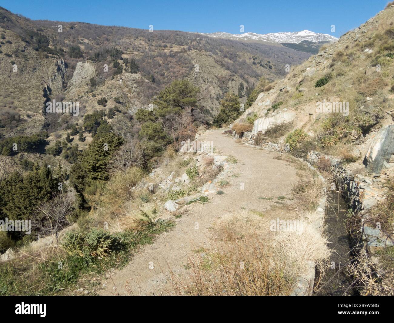 Un sentiero accanto ad un canale di irrigazione acequia, Sierra Nevada montagne vicino Soportujar, valle Alpujarra, Andalusia, Spagna Foto Stock