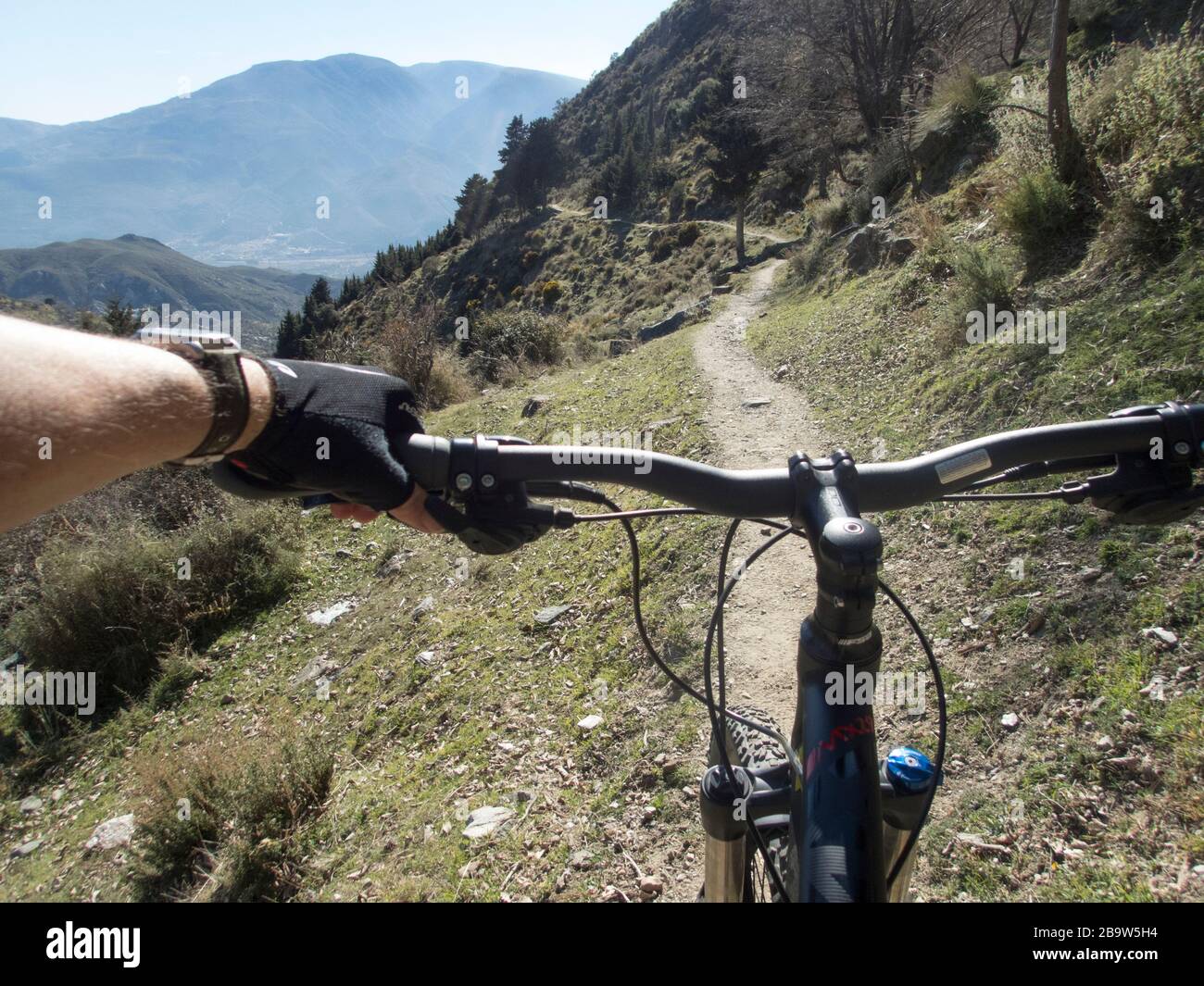 Una mano maschile sul manubrio di una mountain bike su un sentiero nella valle di Alpujarra tra Cañar e Lanjaron, Granada, Andalusia, Spagna Foto Stock