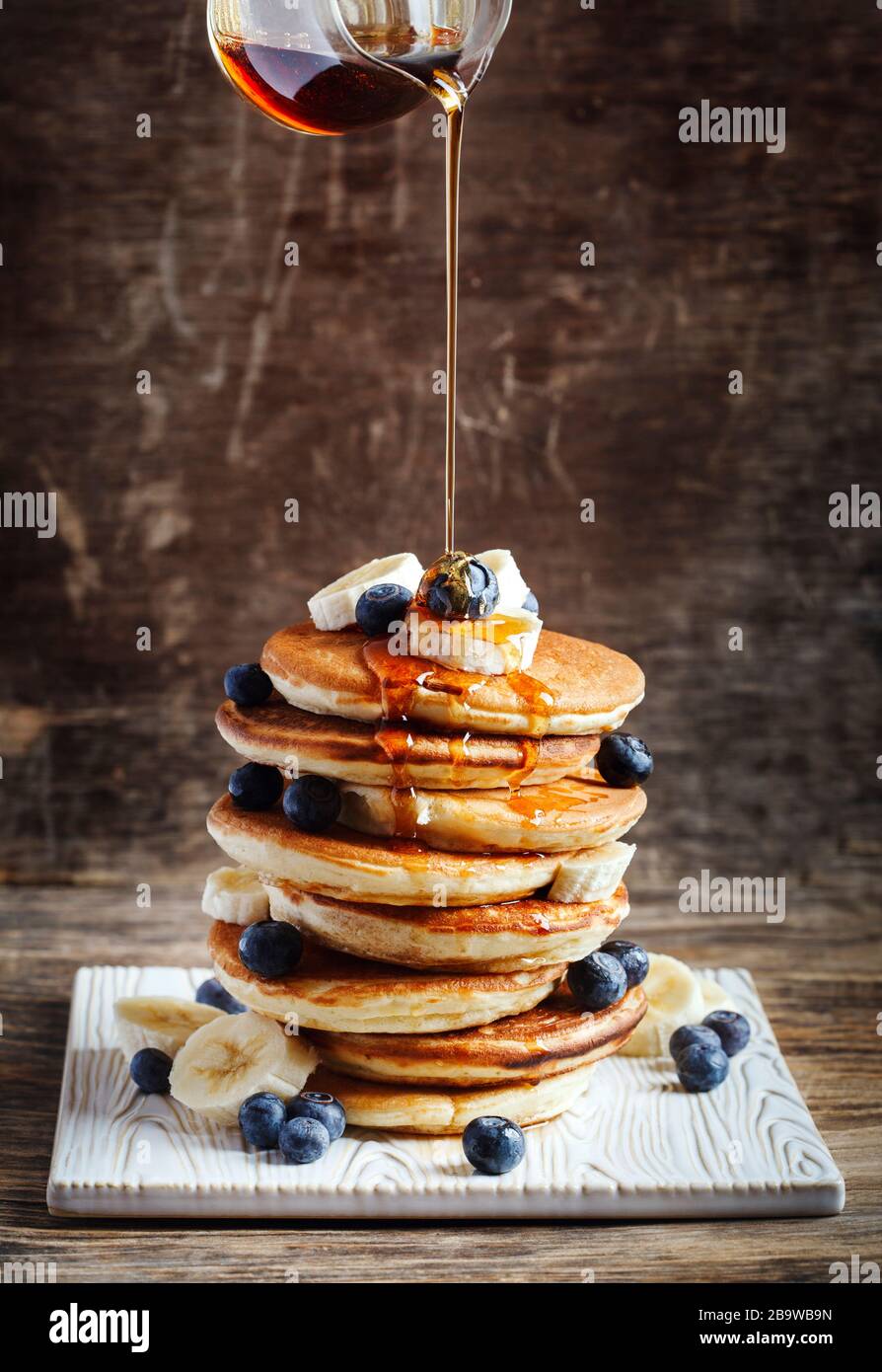 Frittelle con banana, mirtillo e sciroppo d'acero per la colazione. Foto Stock
