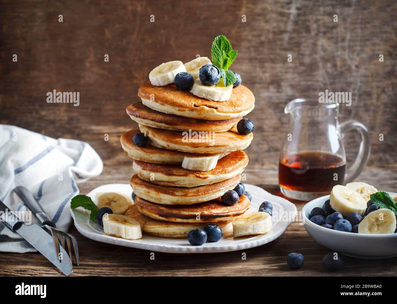 Frittelle con banana, mirtillo e sciroppo d'acero per colazione. Foto Stock