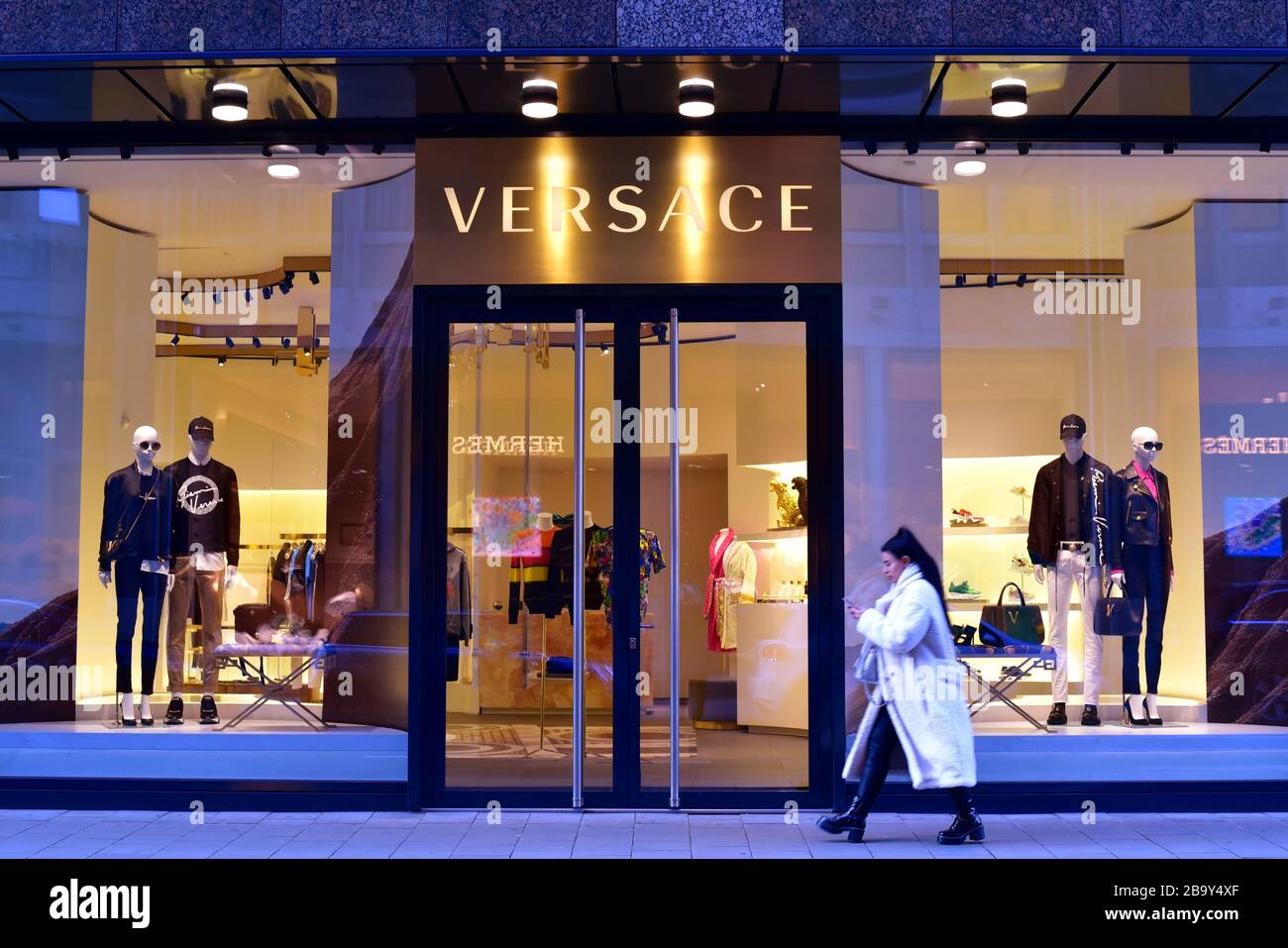 Foto esterna del designer italiano "Versace" a Düsseldorf. Giovane donna che cammina vicino. Foto Stock