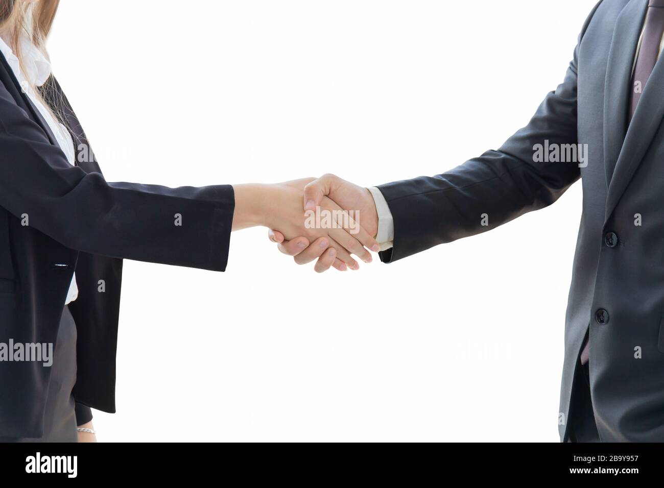 Due giovani uomini e donne d'affari sono vestiti ordinatamente in un vestito e cravatta, in piedi mano nella mano, mostrando simboli di affari separati su uno sfondo bianco. Foto Stock