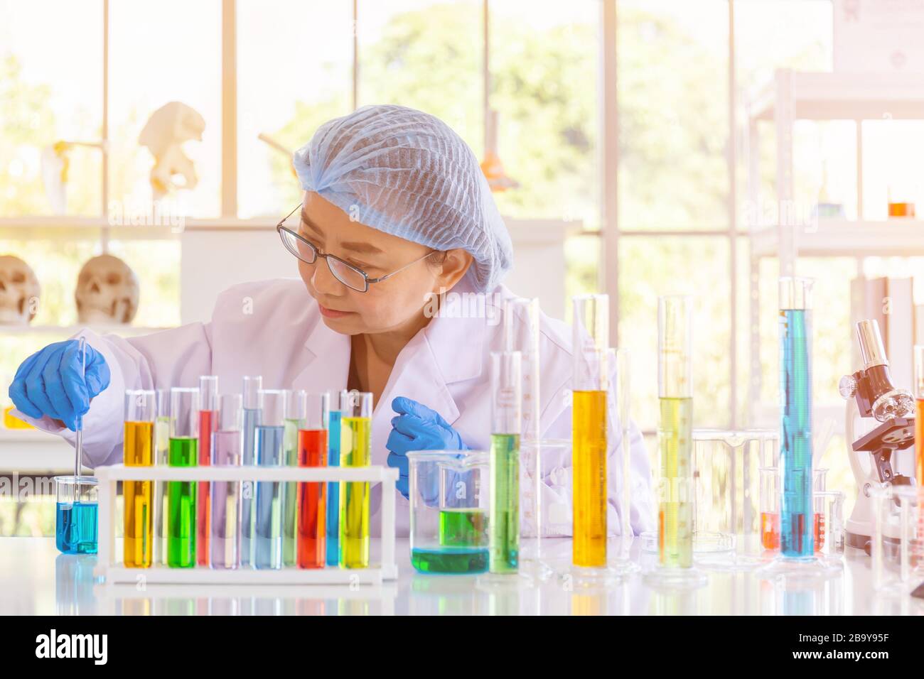 Una scienziata asiatica femminile sta ricercando una formula chimica in un laboratorio. Foto Stock