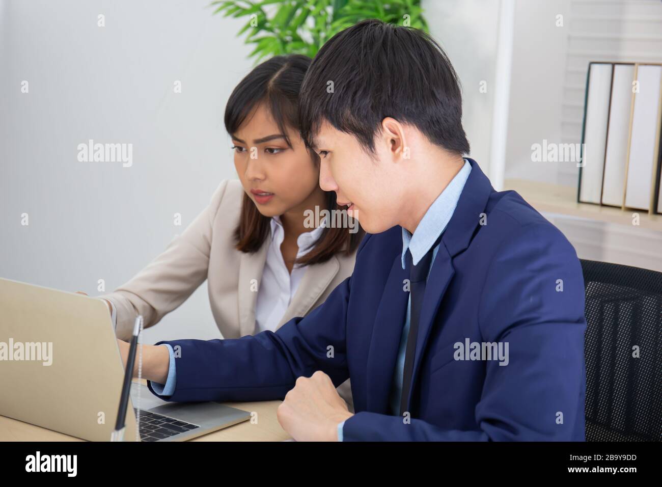 Due uomini e donne del personale asiatici hanno aiutato a pianificare un tavolo pieno di documenti e tablet, notebook. Foto Stock