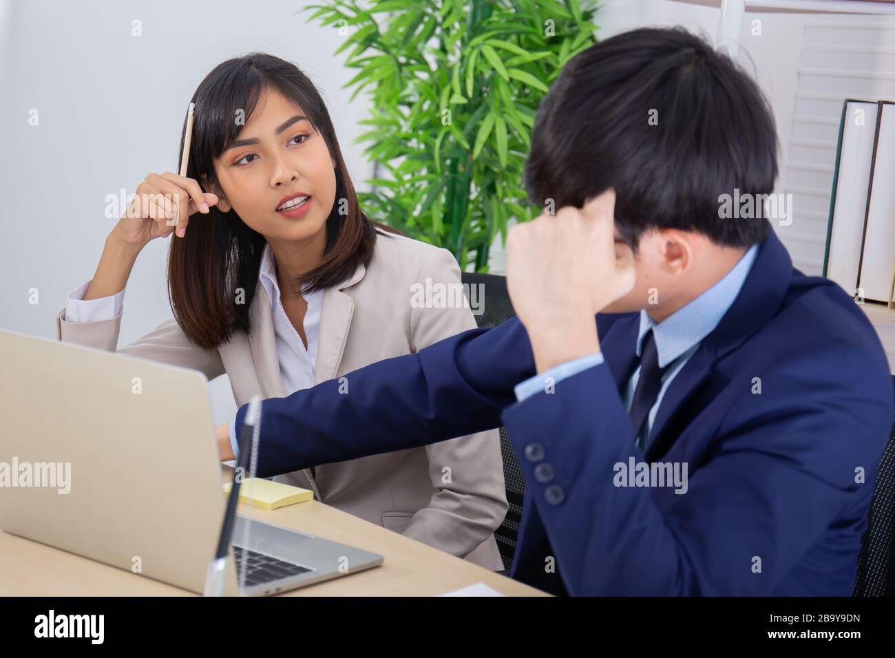 Due uomini e donne del personale asiatici hanno aiutato a pianificare un tavolo pieno di documenti e tablet, notebook. Foto Stock