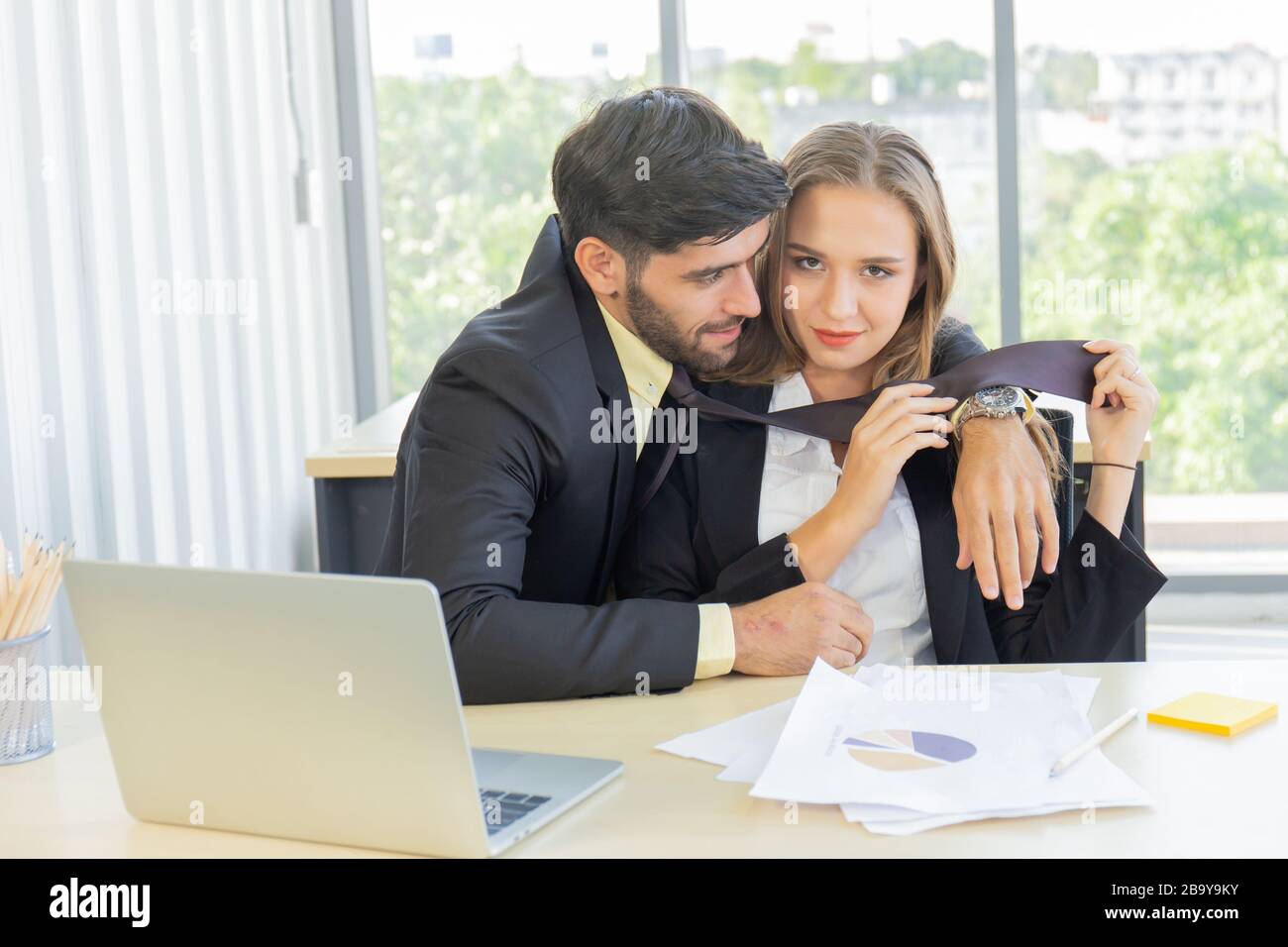 Due giovani uomini d'affari, uomini e donne, lavorano in ufficio con un tablet e documenti di accompagnamento sulla scrivania con sorrisi e felicità. Foto Stock