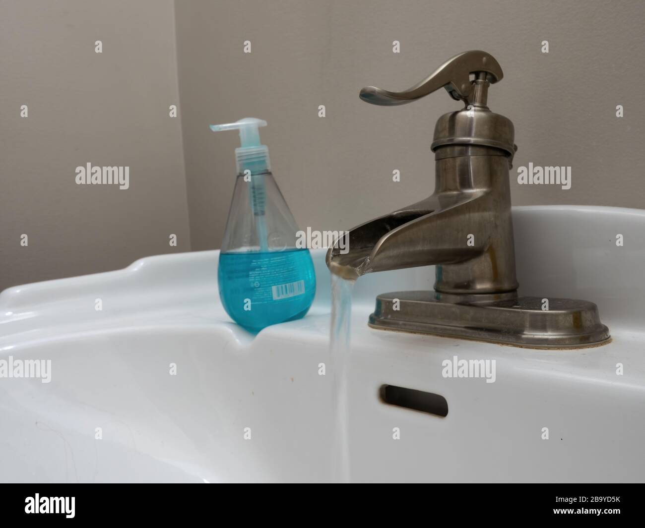 lavarsi le mani in lavello bianco con sapone liquido blu Foto Stock