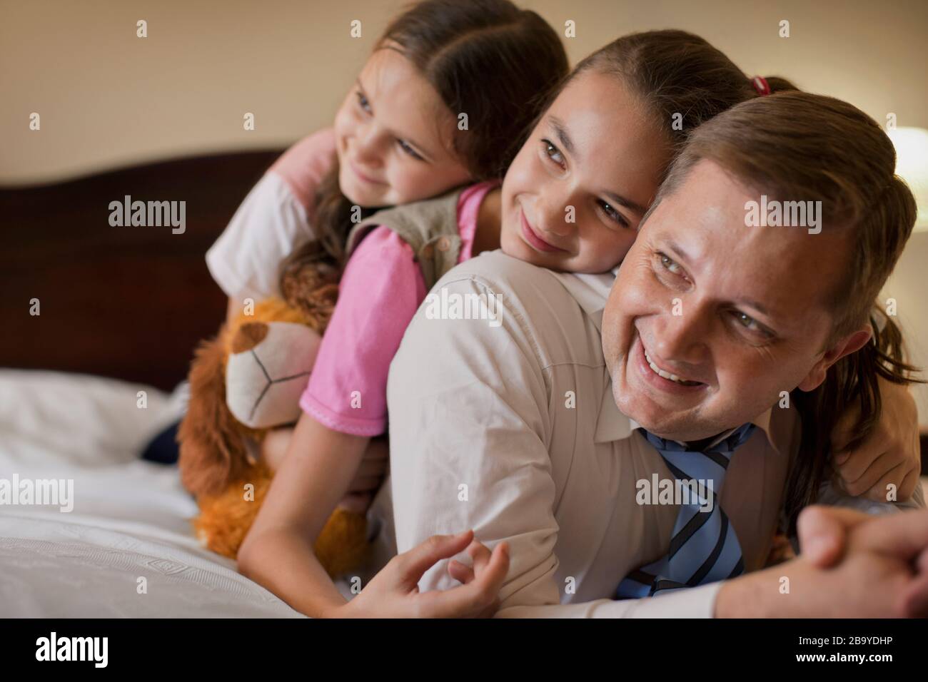 Imprenditore e le sue due giovani figlie giacciono su un letto. Foto Stock