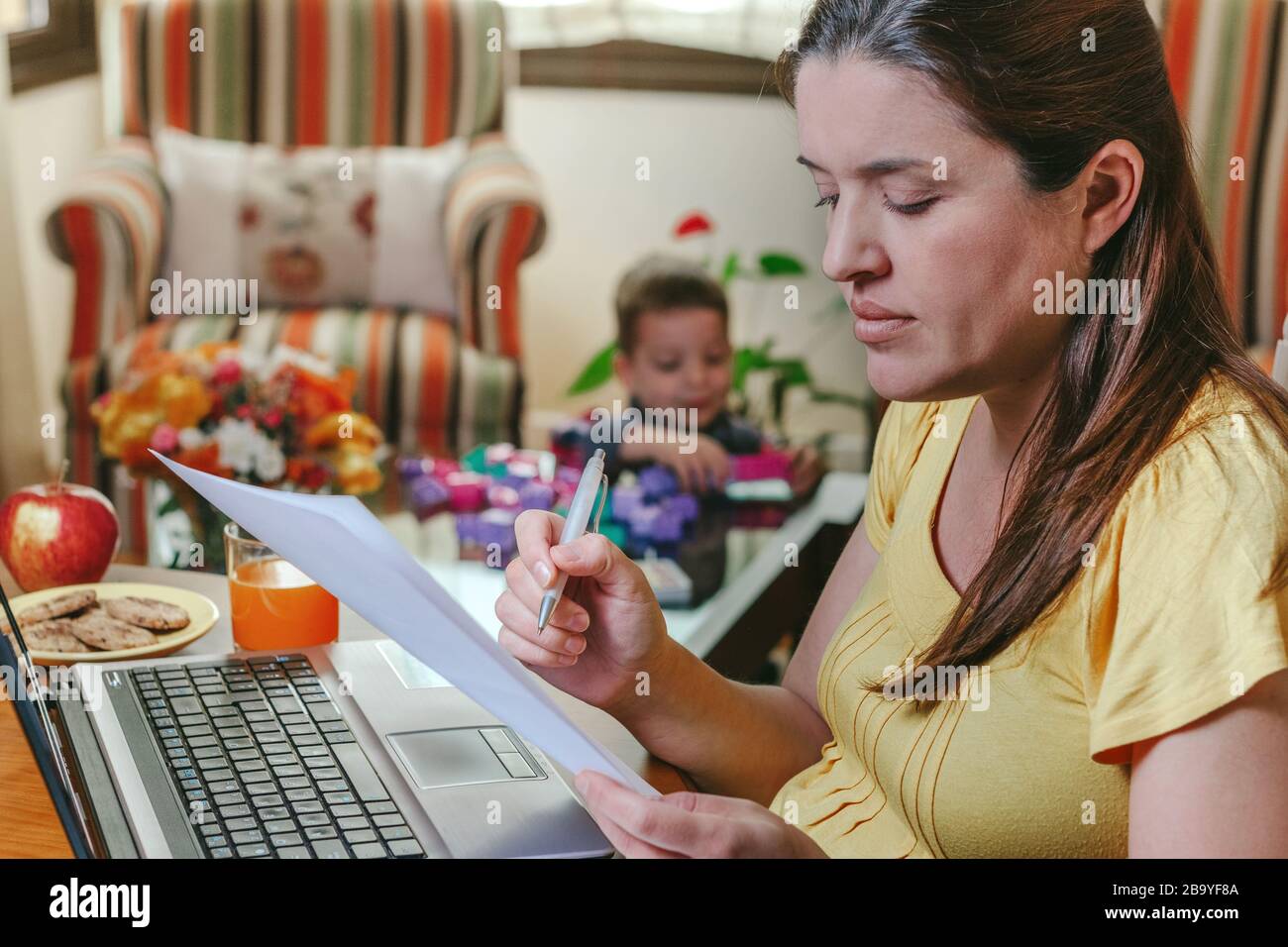 Madre che lavora a casa mentre suo figlio gioca Foto Stock