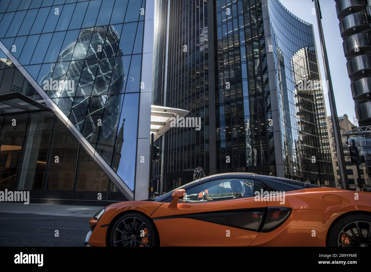 Londra, Regno Unito. 25 Marzo 2020. Un uomo guida una macchina sportiva su una strada vuota nel quartiere finanziario di Londra, normalmente molto trafficato, il giorno dopo l'annuncio delle restrizioni di uscita contro la diffusione del coronavirus. Il primo Ministro Johnson istruì i suoi connazionali a lasciare la casa il meno possibile Credit: Oliver Weiken/dpa/Alamy Live News Foto Stock