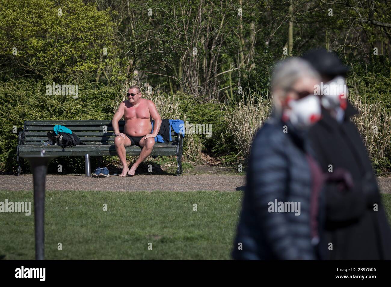 Londra, Regno Unito. 25 Marzo 2020. Un uomo sunbathes in Regents Park il giorno dopo l'annuncio delle restrizioni di uscita contro la diffusione del coronavirus. Il primo Ministro Johnson istruì i suoi connazionali a lasciare la casa il meno possibile Credit: Oliver Weiken/dpa/Alamy Live News Foto Stock