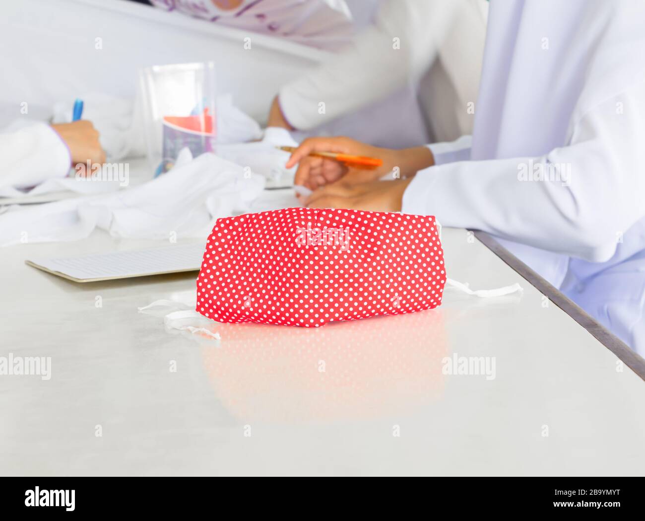 Primo piano. Mascherare il tessuto a righe rosso a punta sul tavolo. Prevenire il coronavirus o la profilassi concettuale (Covid-2019) Foto Stock