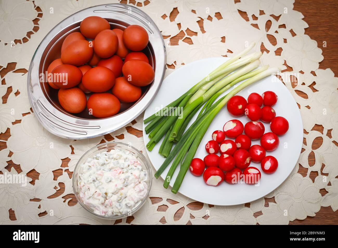 Tradizionale colazione di Pasqua, un mazzo di uova di pollo lesse dipinte con cipolle giovani, ravanelli e insalata francese sul tavolo. Foto Stock