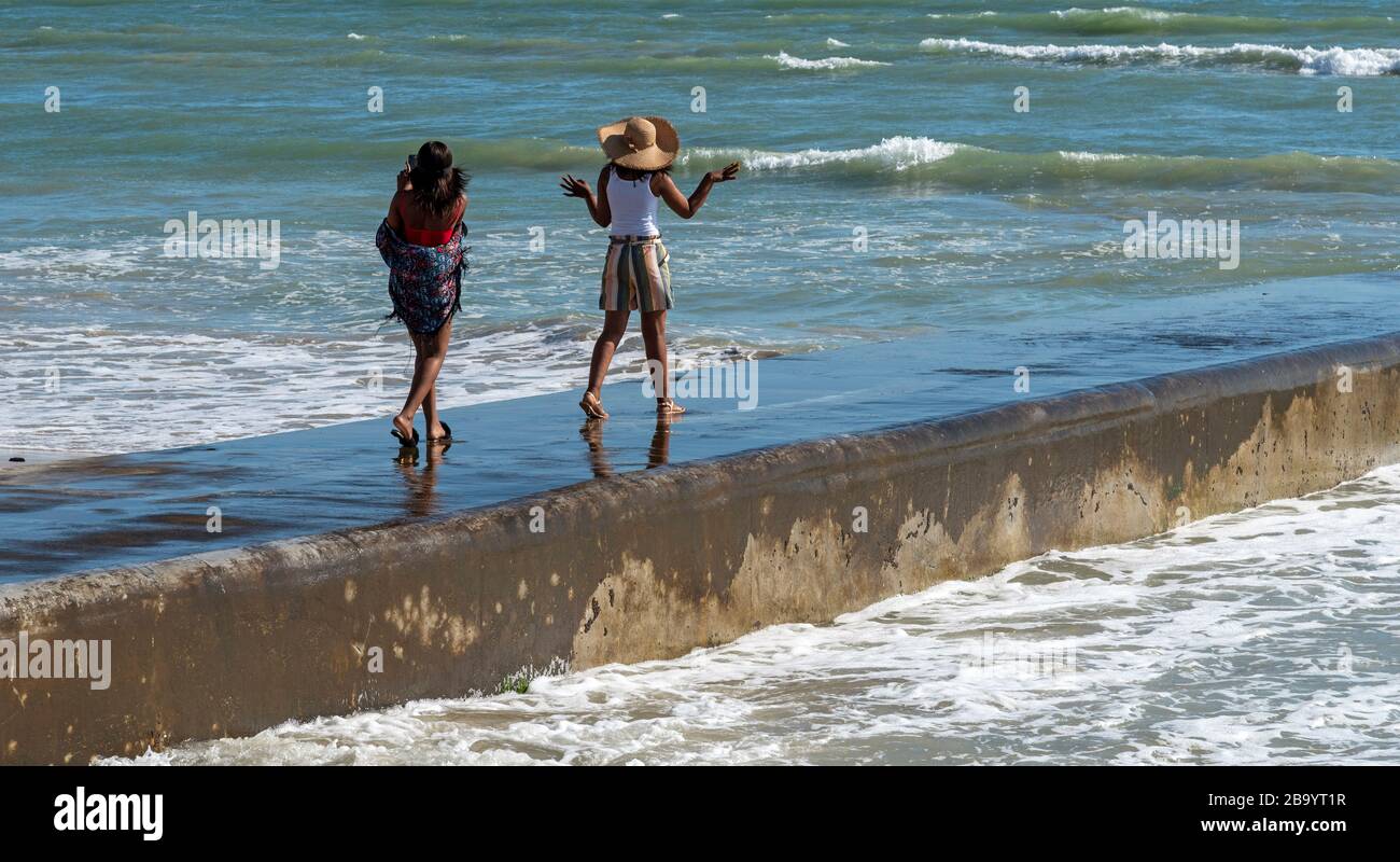 Strand, Somerset West, western cape, Sud Africa. Dic 2019. Giovani ragazze che si divertono a camminare lungo il muro di mare a Strand, Somerset West, Sud Africa Foto Stock