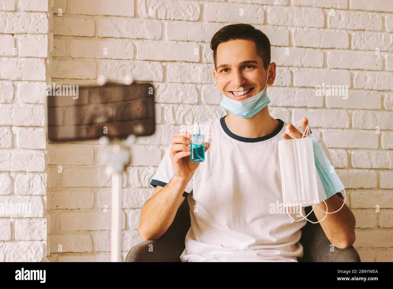 Bel blogger registrazione video istruzioni su come usare sanitizzatore e maschere di protezione medica come misure preventive e la protezione contro coronavi Foto Stock