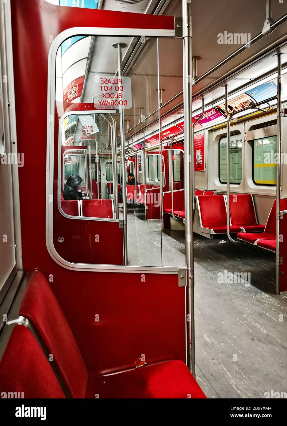 Poche persone che cavalcano vicino al treno della metropolitana TTC vuoto e che tengono le distanze sociali a Toronto durante Covid-19 a.k.a. romanzo coronarirus pandemic il 24 marzo 2020. Stato di emergenza per la città Foto Stock