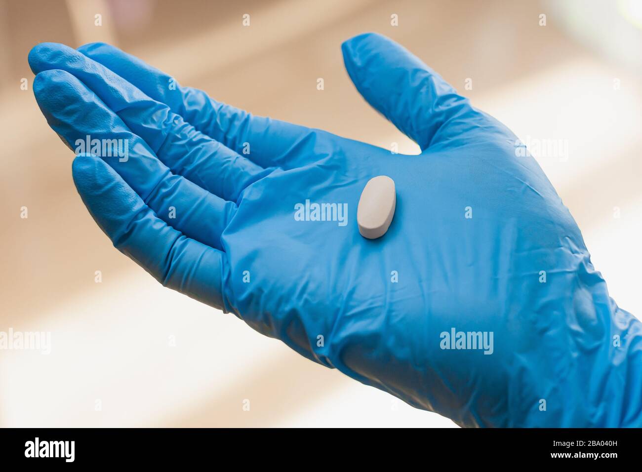 Pillole in mano donna in guanti blu. Vitamine o medicinali per il trattamento del coronavirus. Foto Stock