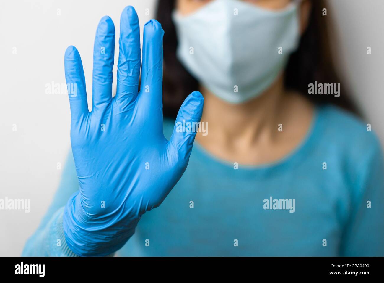 Donna mostra STOP in guanti blu e maschera protettiva nella lotta con coronavirus, 2019-nCoV, SARS-Cov-2, influenza. Concetto di salute e bene Foto Stock