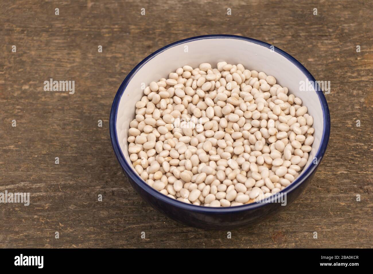 Un piatto di fagioli crudi su sfondo di legno, Beans benefici Foto Stock