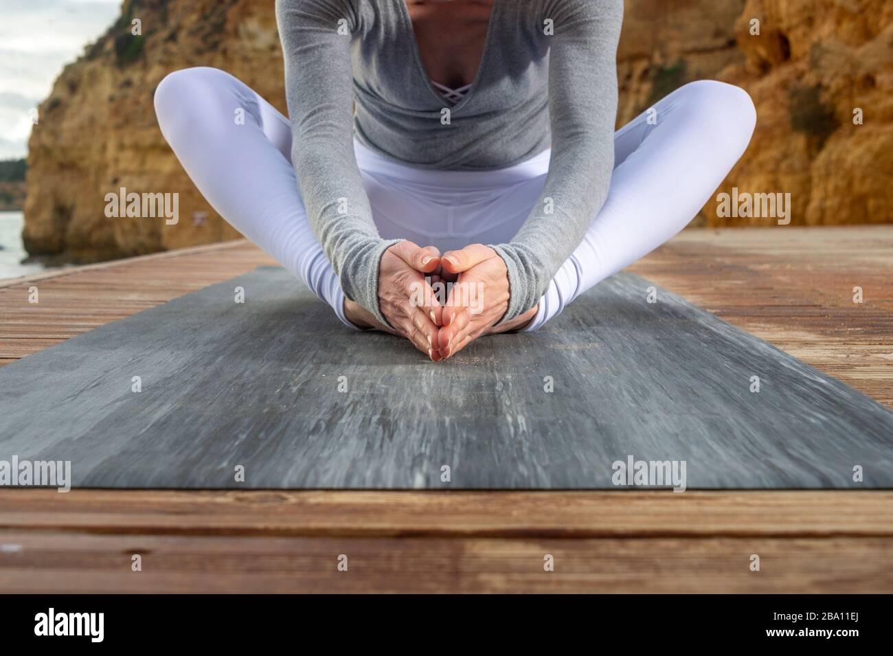 Primo piano di una donna che fa la farfalla yoga posa fuori Foto Stock