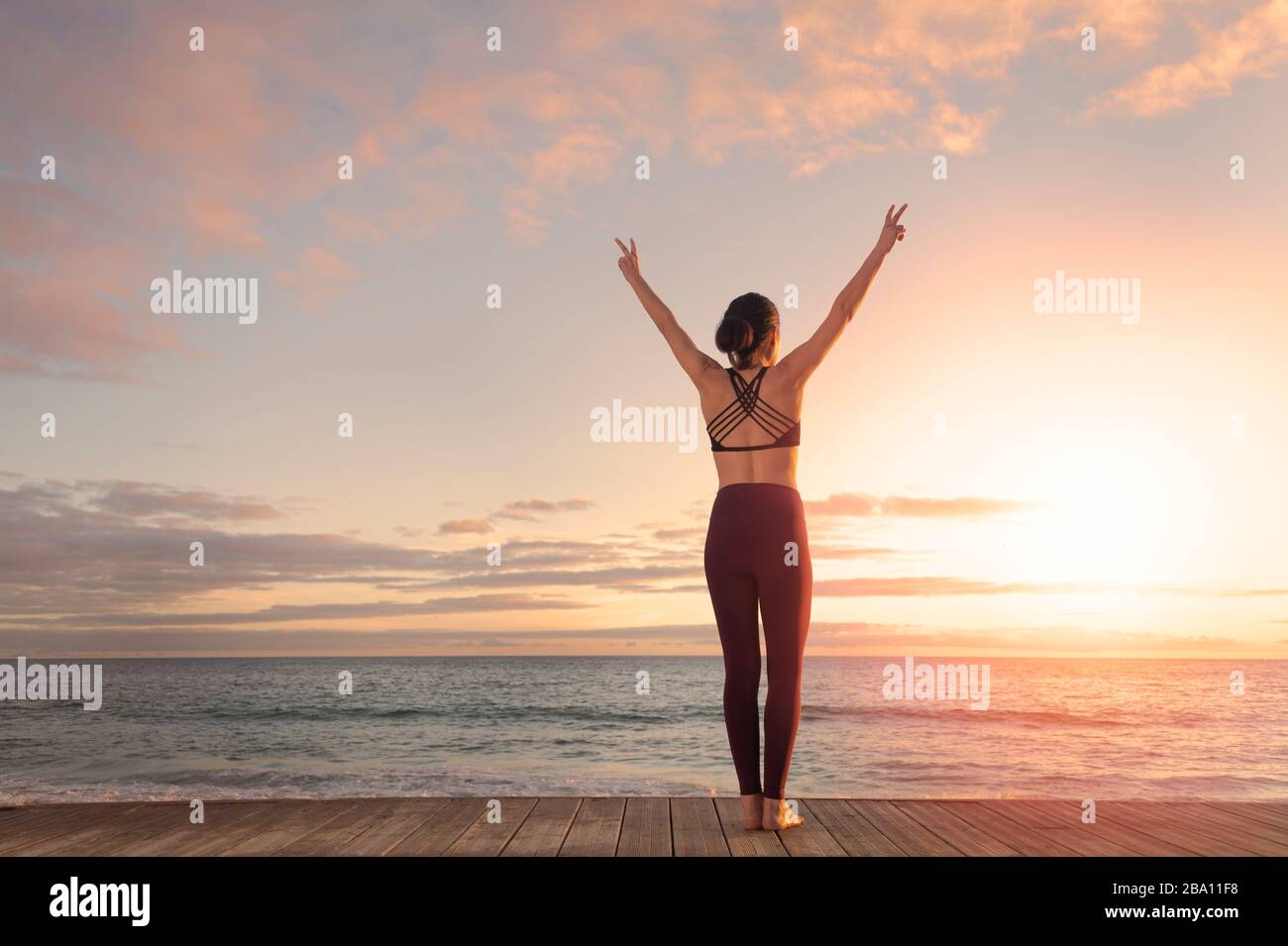 donna sportiva con le braccia sollevate in piedi dal mare, sucessa, libertà. Foto Stock