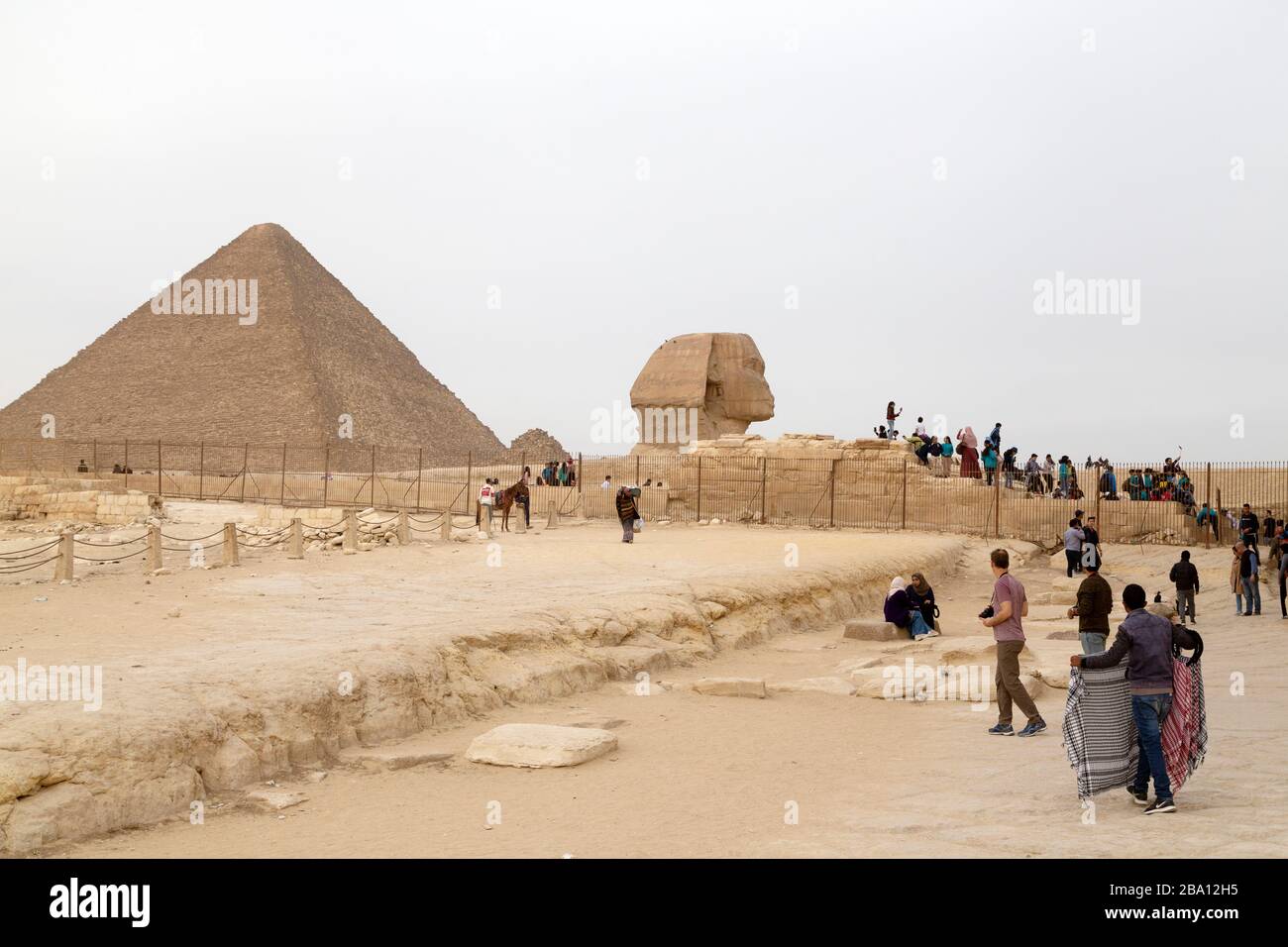 Venditori di souvenir e turisti presso la Grande Sfinge di Giza, vicino alla Grande Piramide, all'Altopiano di Giza al Cairo, Egitto. Foto Stock