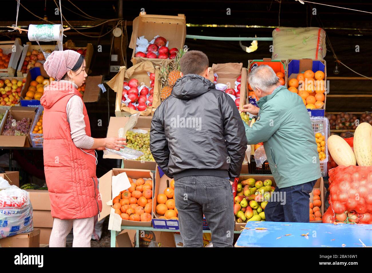 Guida turistica e selezione di frutta fresca in stallo mercato vicino a Bishkek, Kirghizistan in Asia centrale. Locale Asia donna vendere per straniero. Foto Stock
