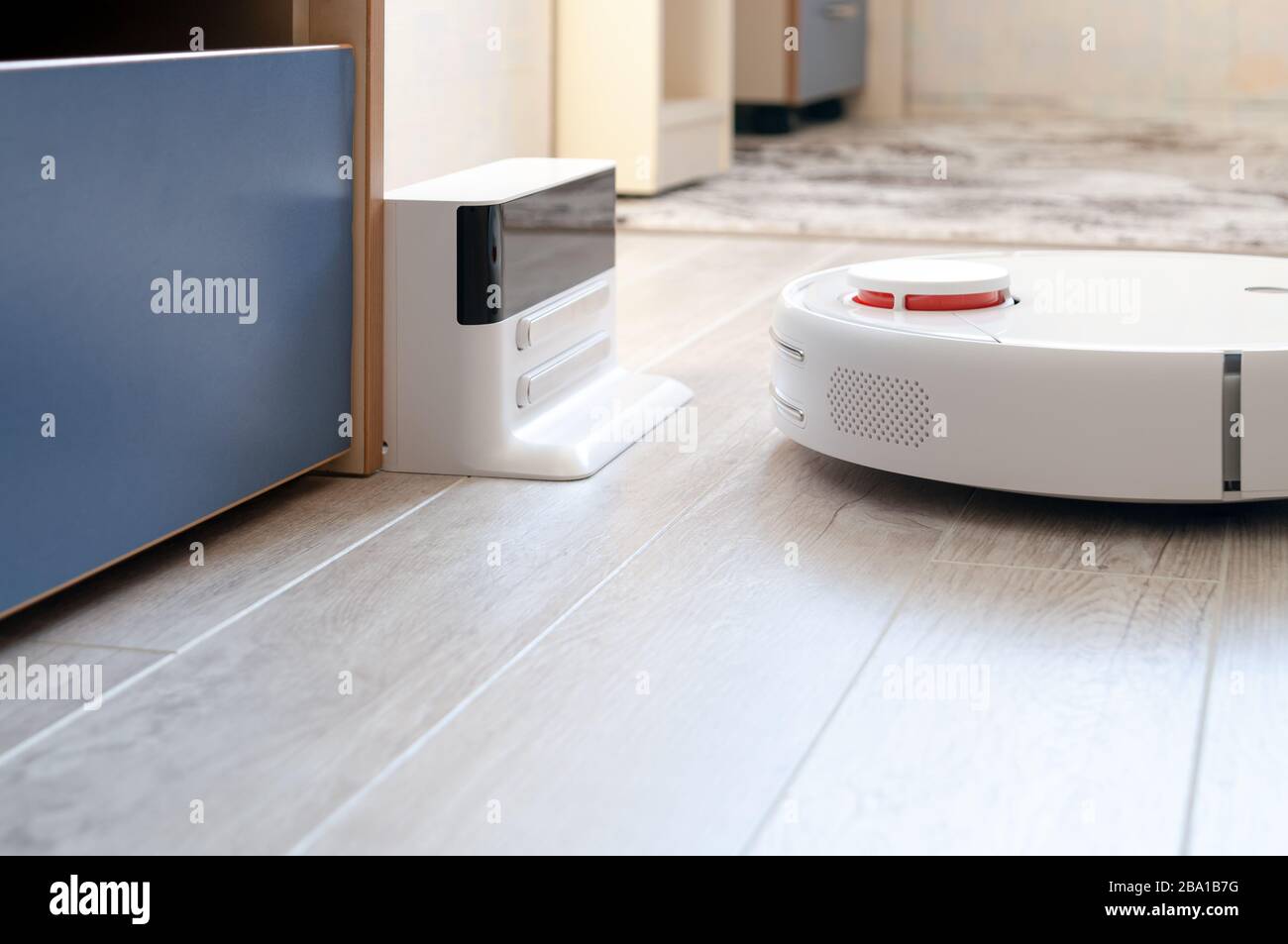 Aspirapolvere roboticobotico rotondo bianco su laminato - tecnologia per la casa Foto Stock