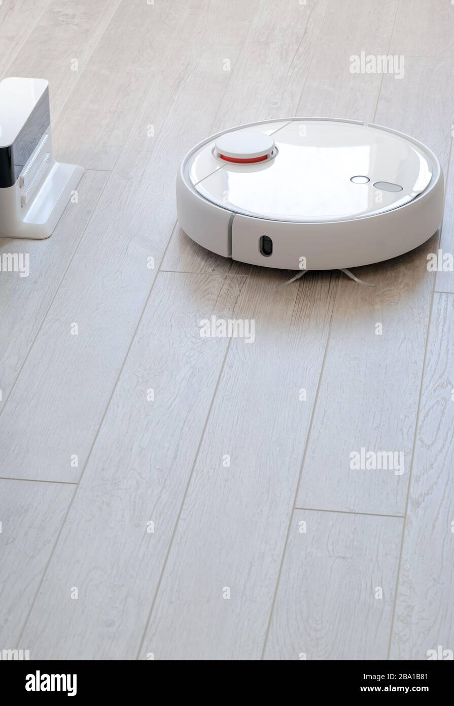 Aspirapolvere roboticobotico rotondo bianco su laminato - tecnologia per la casa Foto Stock