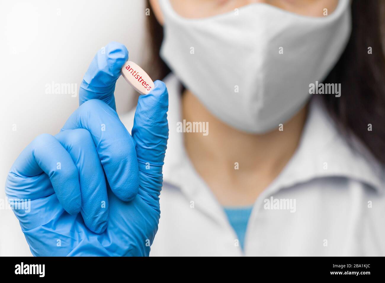 Pillola antistress in mano in guanti blu. La femmina sta tenendo un medicinale. Farmaci contro il coronavirus, 2019-nCoV, SARS-nCov, COVID-2019 outbreaking. Foto Stock