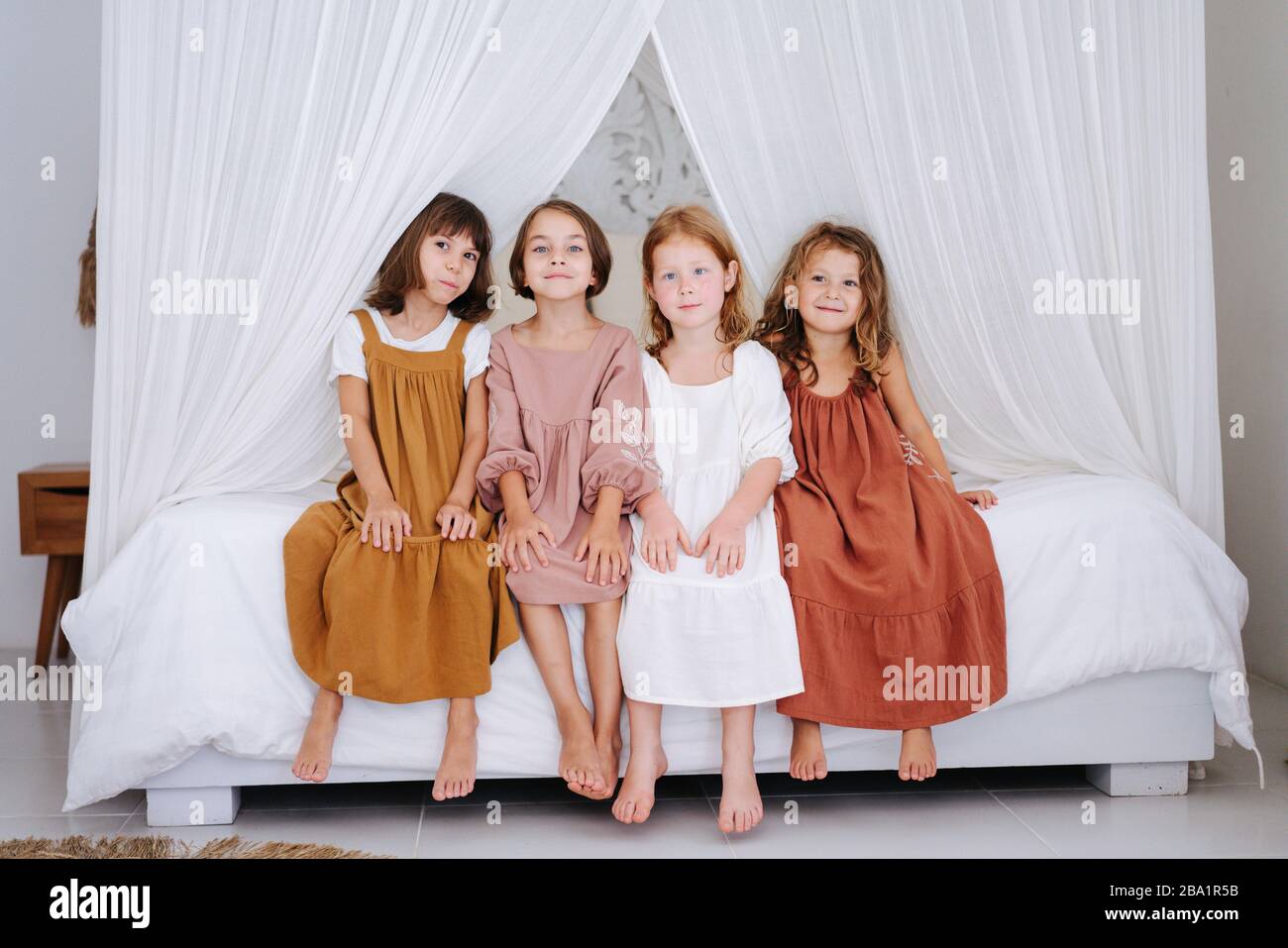 Quattro ragazze carine circa la stessa età seduto su un letto matrimoniale  con tende Foto stock - Alamy