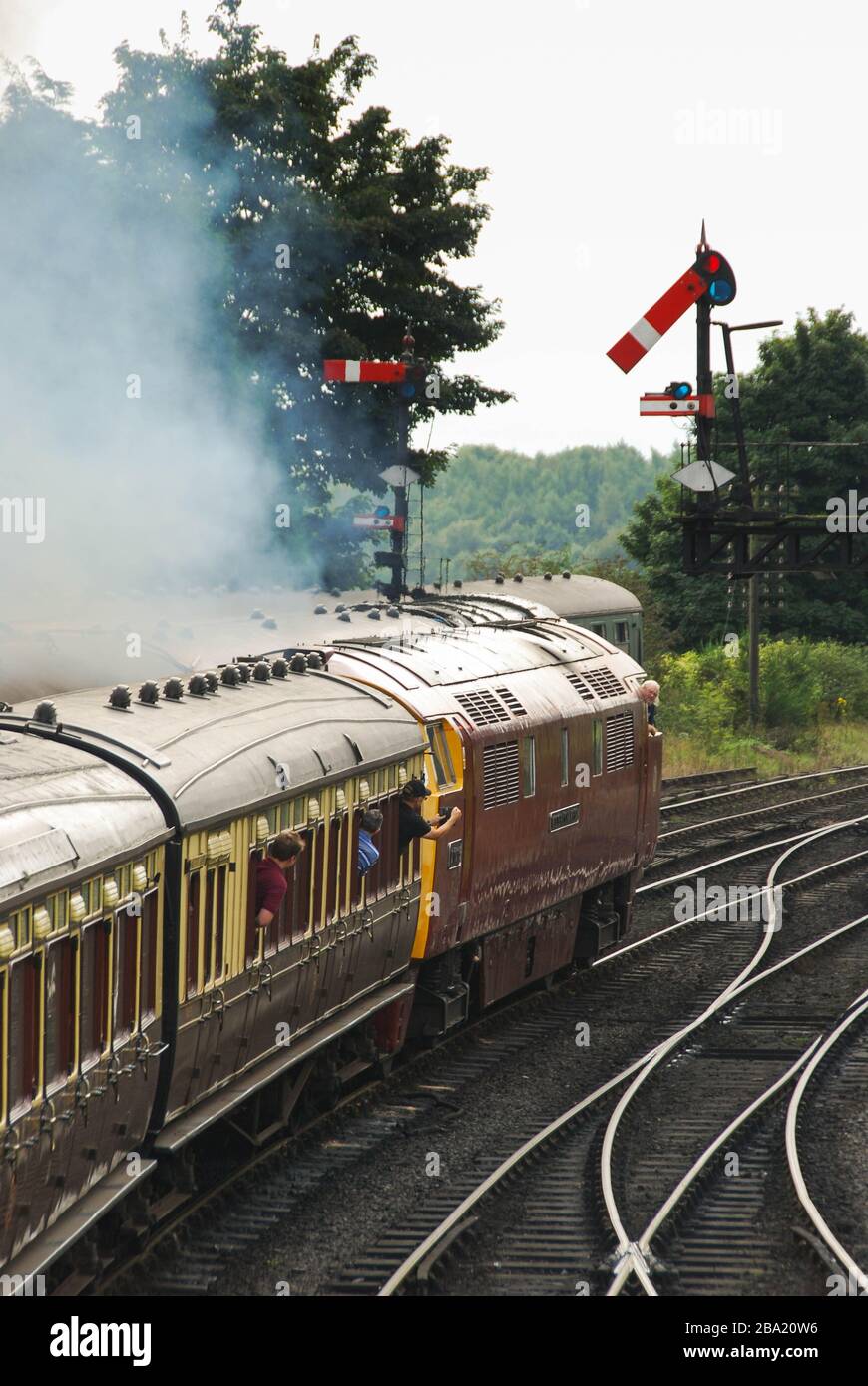 Bridgenarth, Inghilterra - Agosto 2016: Un treno trainato da una locomotiva diesel di Classe Occidentale che passa un portale di segnale sulla Severn Valley Railway Foto Stock