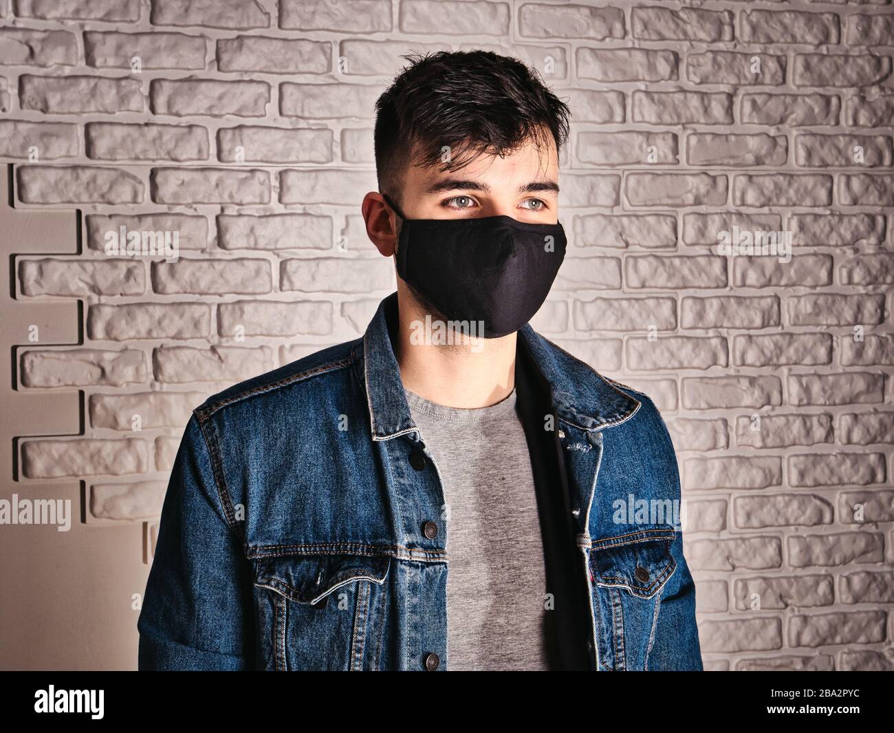 Giovane uomo in maschera medica contro muro bianco Foto Stock
