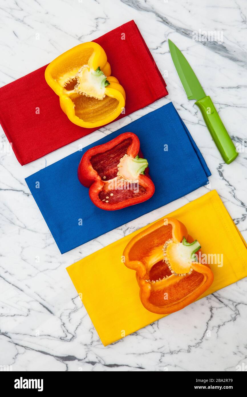 peperoni gialli, arancioni e rossi con coltello da parare su bancone in marmo Foto Stock