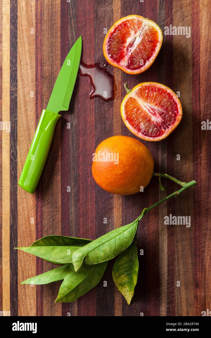 arance del sangue a fette e coltello da taglio su un tagliere di legno Foto Stock