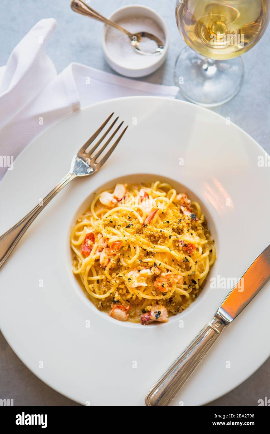 spaghetti con aragosta, bisque di aragosta e nori pangrattato e un bicchiere di chardonnay Foto Stock