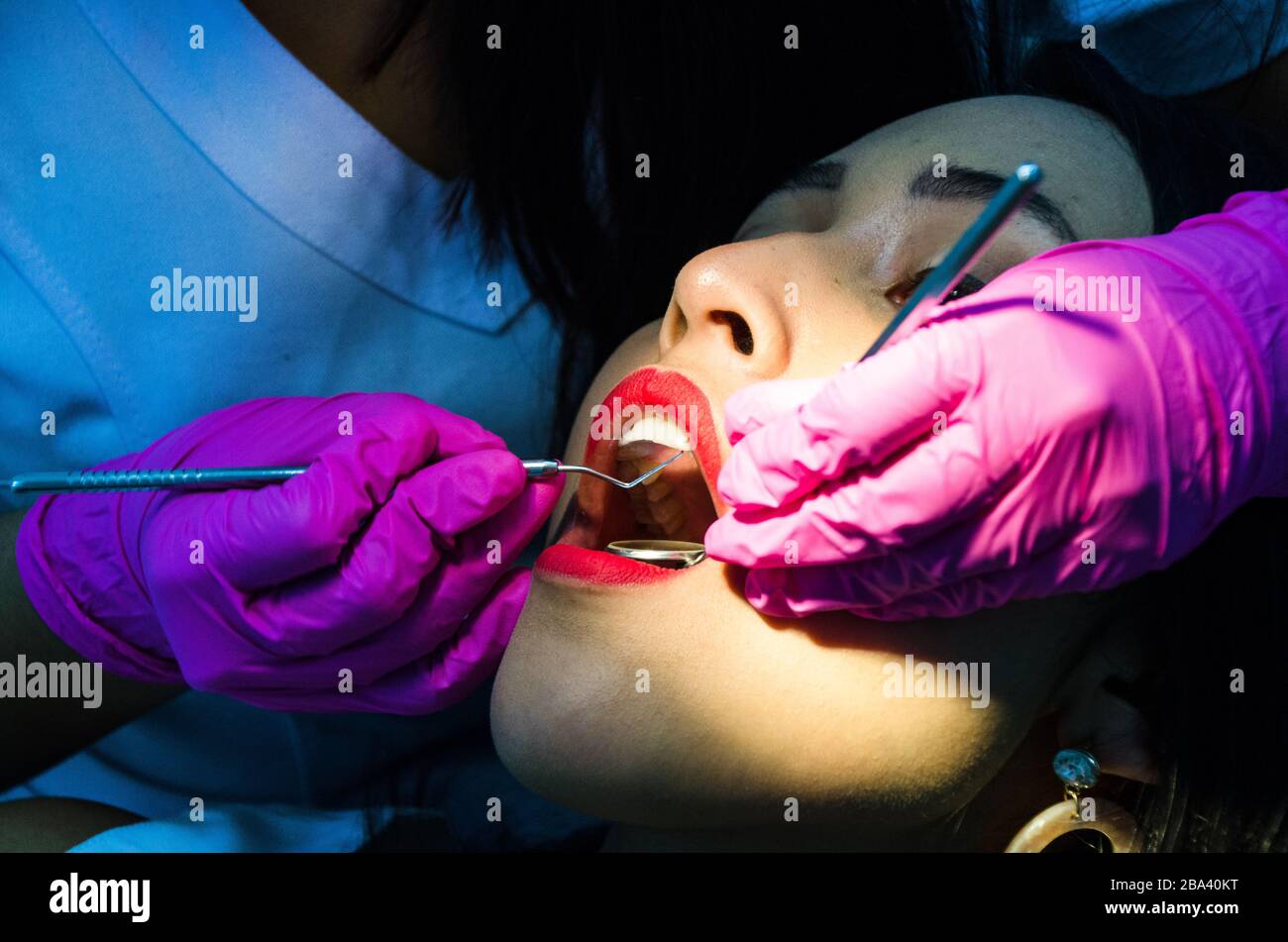 Giovane paziente femminile prende una presenza dentale nell'ufficio del dentista Foto Stock