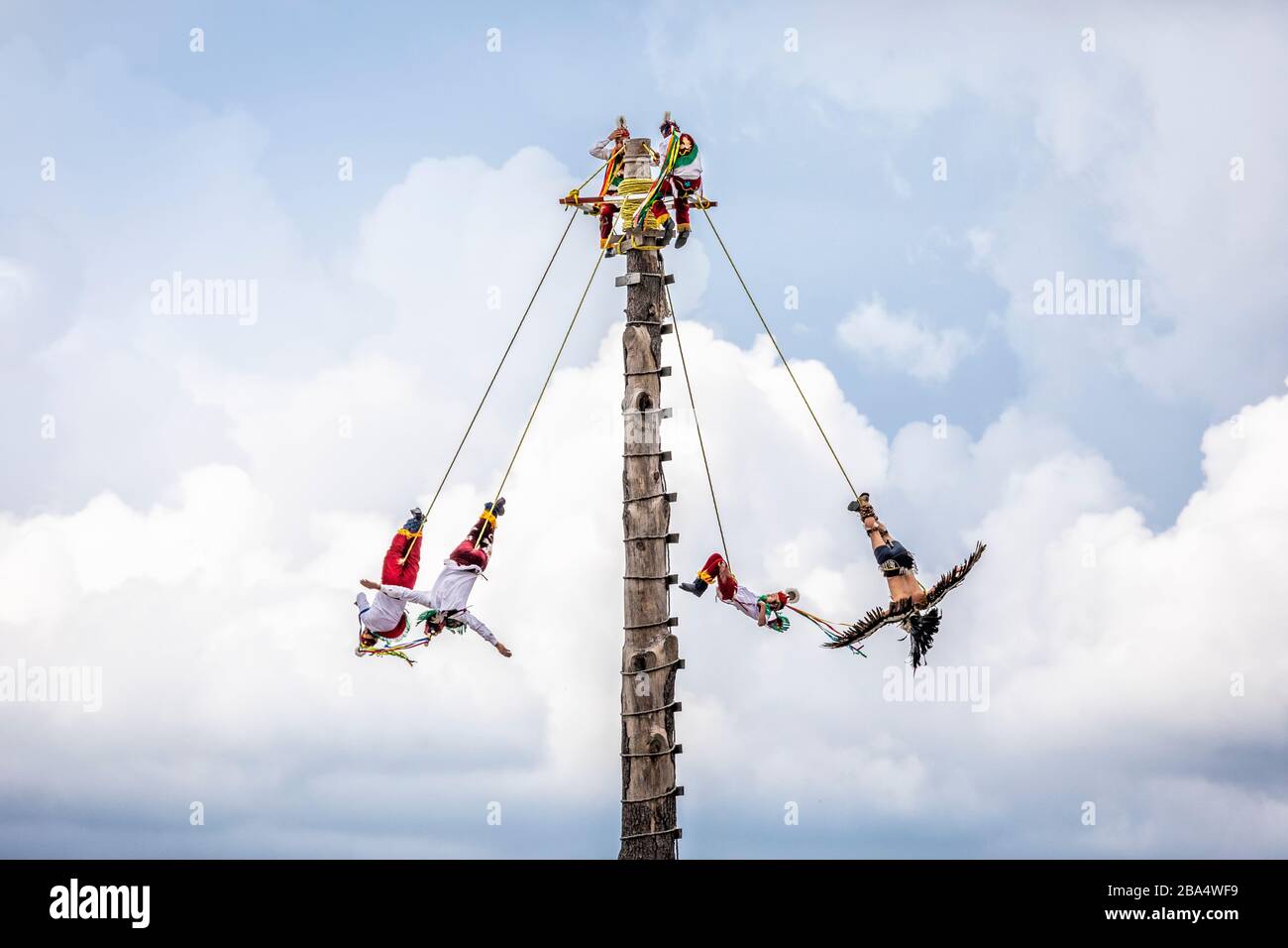 I voladores o i flirers girano intorno ad un palo di legno mentre scendono alla terra in un rituale tradizionale di Cuetzalan, Puebla, Messico. Foto Stock