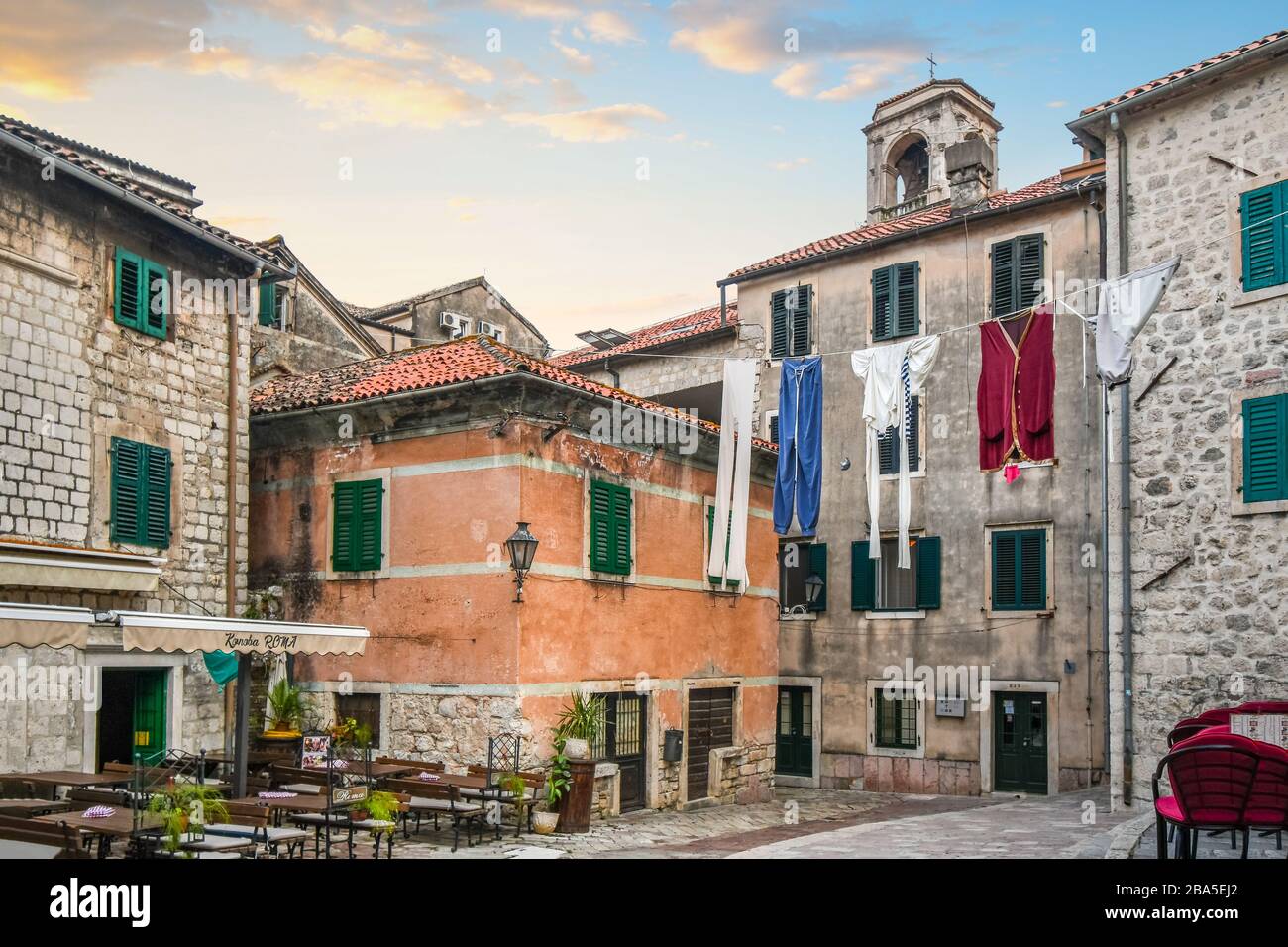 Un display di grandi dimensioni del servizio lavanderia pende su una piccola piazza del villaggio vicino a una caffetteria nella città medievale di Kotor, Montenegro. Foto Stock