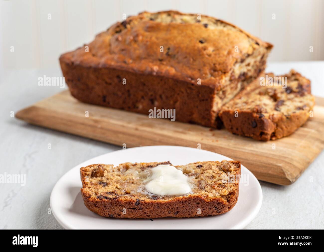 Fetta di pane di banana appena sfornato con burro Foto Stock