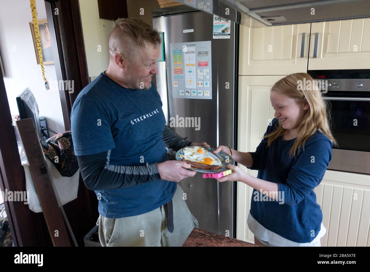 Padre che stuzzicava la figlia che voleva la sua colazione appena cucinata con pancetta e uova. Zawady Gmina Rzeczyca Polonia Foto Stock