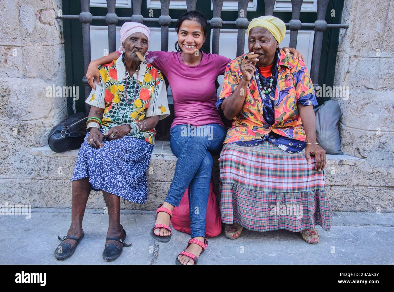 Tourist e due donne cubane che fumano un sigaro, l'Avana, Cuba Foto Stock